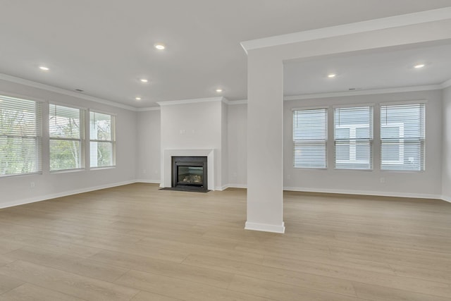 unfurnished living room with light wood-type flooring, a fireplace with flush hearth, baseboards, and crown molding