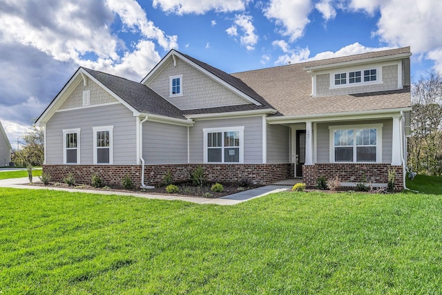 craftsman-style house featuring brick siding, a front yard, and a shingled roof