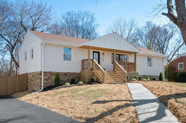 view of front of house featuring covered porch, fence, and brick siding