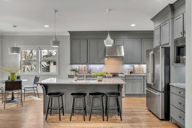 kitchen with under cabinet range hood, stainless steel appliances, a sink, a kitchen breakfast bar, and gray cabinets