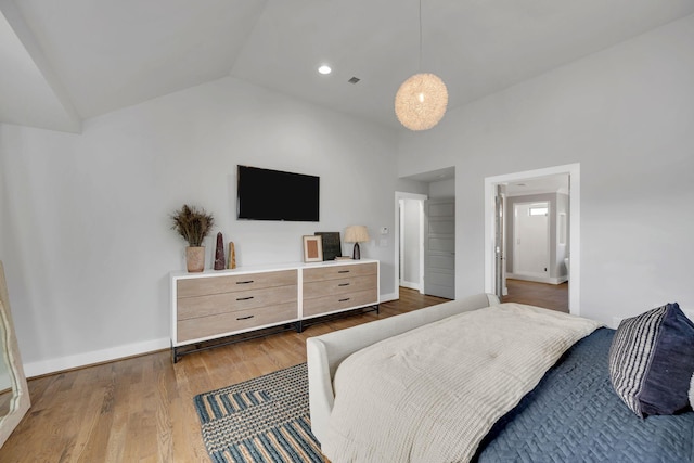 bedroom featuring vaulted ceiling, wood finished floors, visible vents, and baseboards