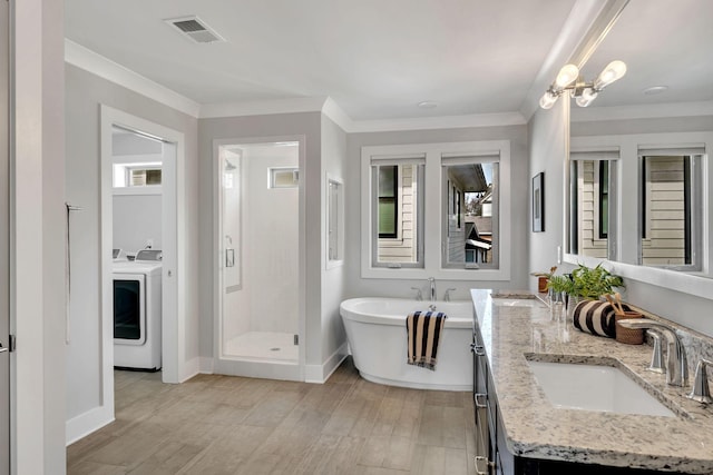 bathroom featuring a sink, visible vents, ornamental molding, a shower stall, and washer / clothes dryer