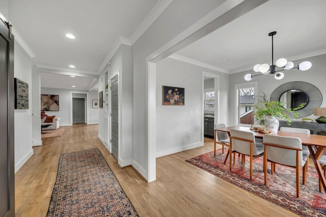 dining space featuring crown molding, light wood-style flooring, and an inviting chandelier