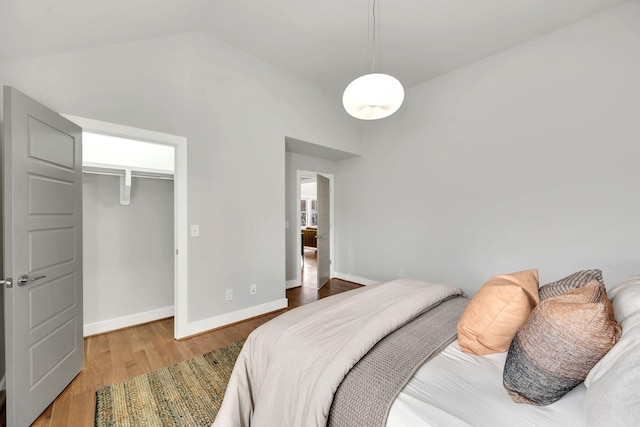 bedroom with lofted ceiling, baseboards, and wood finished floors