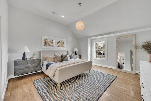 bedroom featuring lofted ceiling, baseboards, visible vents, and light wood finished floors