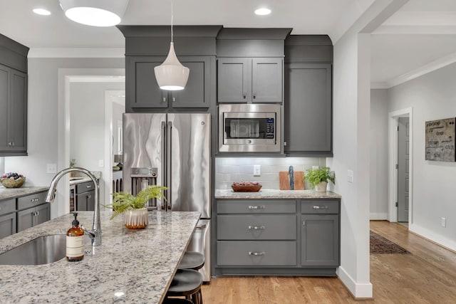 kitchen with appliances with stainless steel finishes, decorative backsplash, a sink, and gray cabinetry