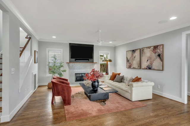 living area featuring plenty of natural light, a fireplace, stairway, and wood finished floors