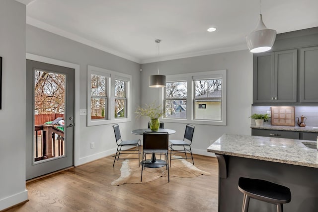 dining space featuring ornamental molding, recessed lighting, light wood-style flooring, and baseboards