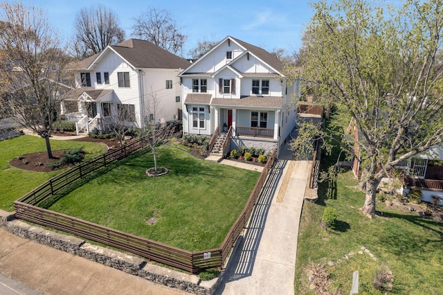 view of front facade featuring stairway, driveway, fence private yard, covered porch, and a front yard