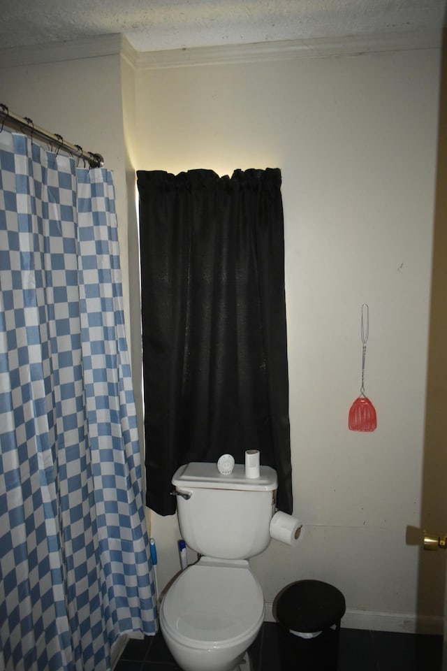 bathroom featuring curtained shower, tile patterned flooring, toilet, baseboards, and crown molding