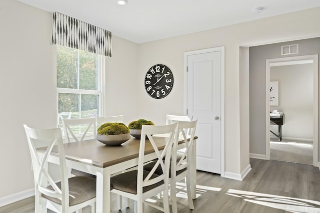 dining space with wood finished floors, visible vents, and baseboards