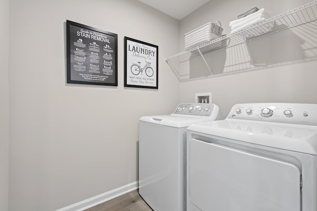 clothes washing area featuring laundry area, baseboards, washer and dryer, and wood finished floors