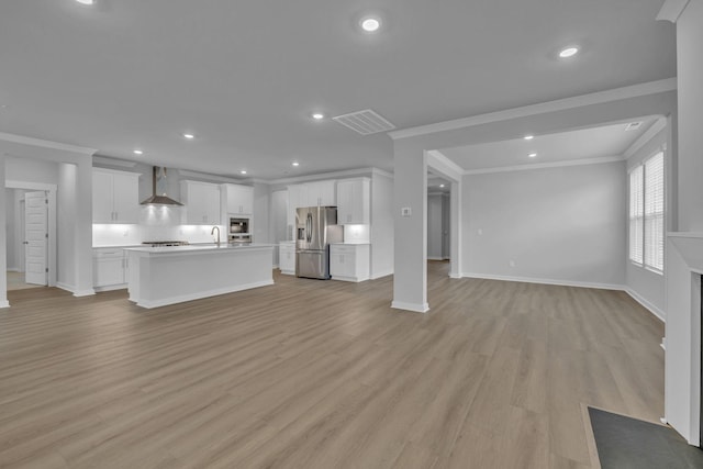 unfurnished living room featuring light wood-style floors, visible vents, crown molding, and a sink