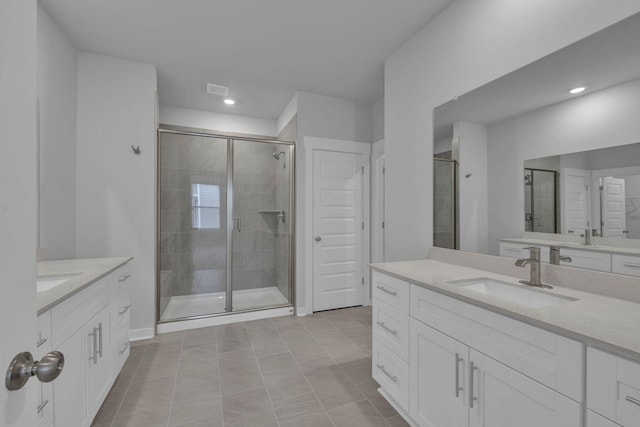 full bath featuring a shower stall, two vanities, a sink, and recessed lighting