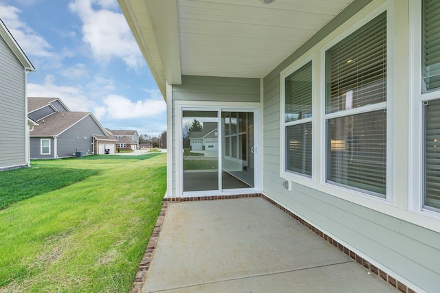 view of exterior entry featuring a lawn and a patio