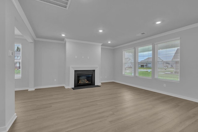 unfurnished living room with light wood-style floors, a fireplace with flush hearth, baseboards, and crown molding