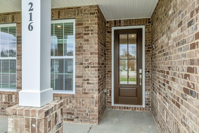 view of exterior entry with covered porch and brick siding