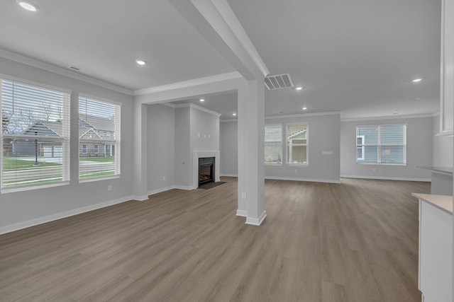 unfurnished living room featuring a fireplace with flush hearth, visible vents, crown molding, and light wood finished floors