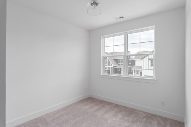 empty room with light carpet, visible vents, and baseboards