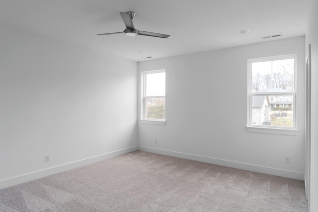 empty room featuring light colored carpet, visible vents, ceiling fan, and baseboards