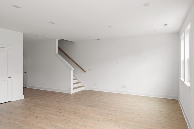 unfurnished room featuring visible vents, baseboards, stairway, and light wood finished floors