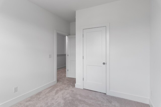 unfurnished bedroom with light colored carpet and baseboards