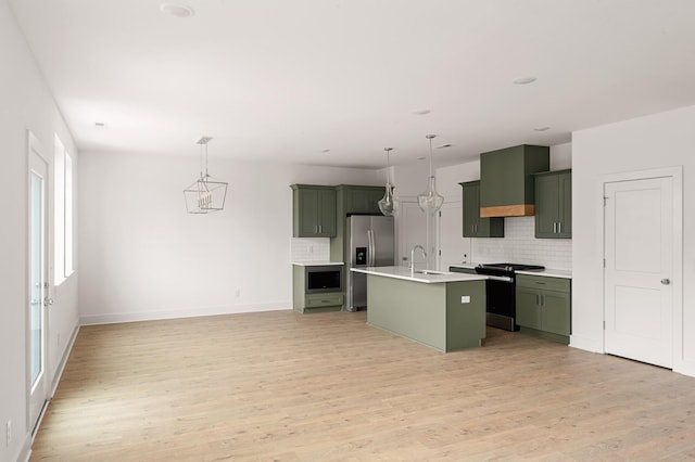 kitchen with light wood finished floors, appliances with stainless steel finishes, light countertops, and green cabinetry