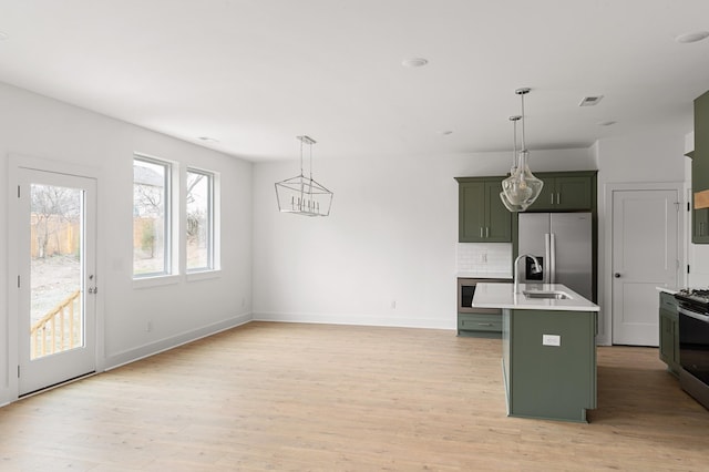 kitchen with light countertops, backsplash, light wood-style flooring, green cabinetry, and stainless steel fridge with ice dispenser