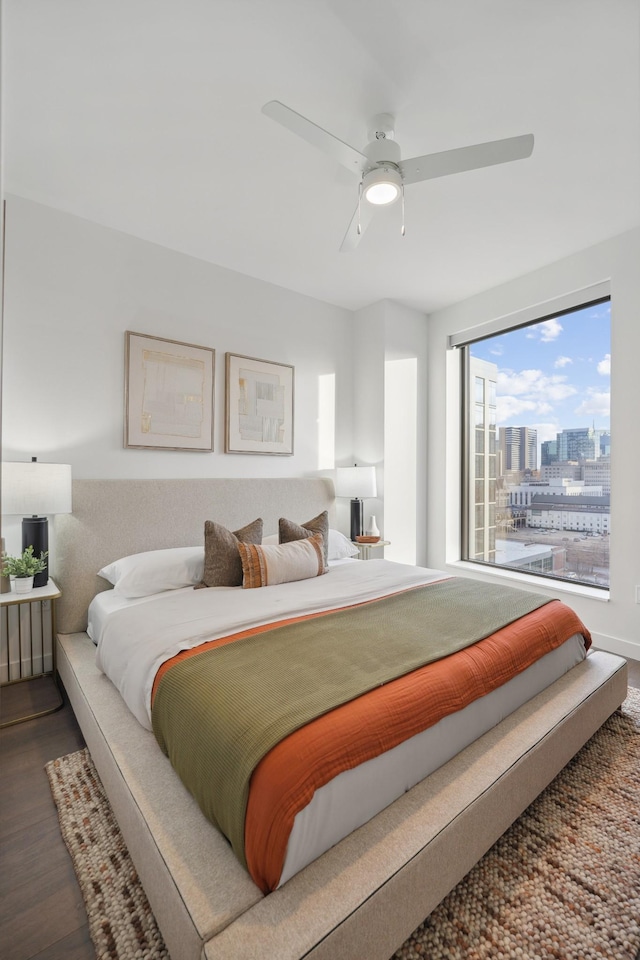 bedroom with a city view, a ceiling fan, and dark wood-style flooring