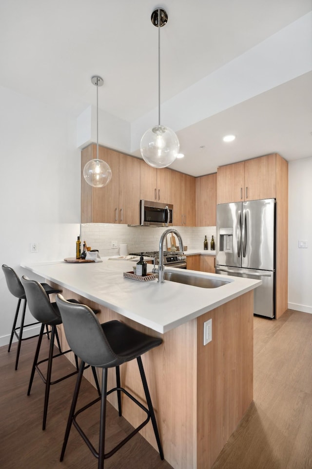 kitchen with light wood finished floors, a kitchen breakfast bar, backsplash, and appliances with stainless steel finishes