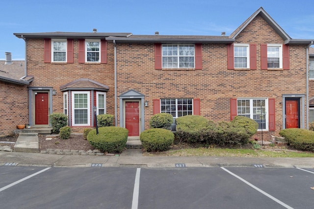 view of property featuring uncovered parking and brick siding