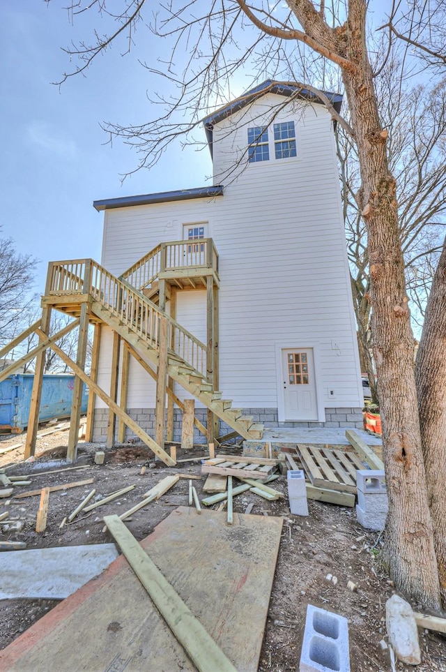 rear view of house with stairs and a wooden deck