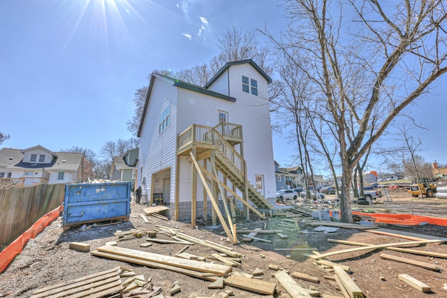 rear view of house featuring fence and stairway