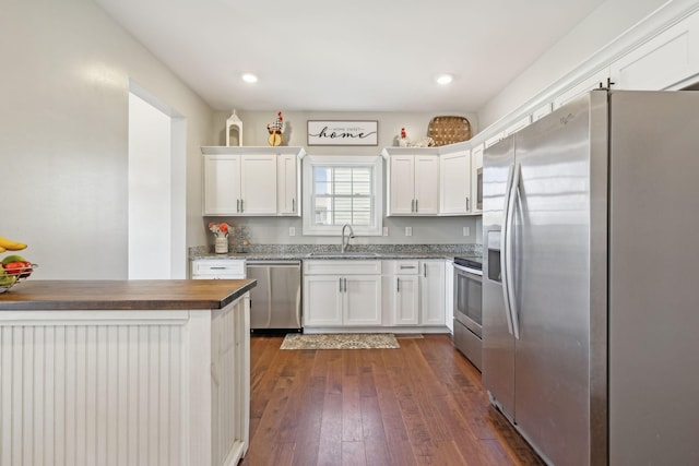 kitchen featuring stainless steel appliances, recessed lighting, dark wood-type flooring, white cabinetry, and a sink