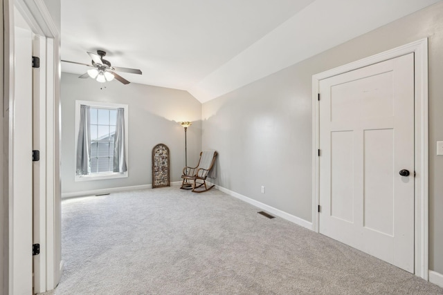 unfurnished room featuring lofted ceiling, carpet floors, a ceiling fan, visible vents, and baseboards