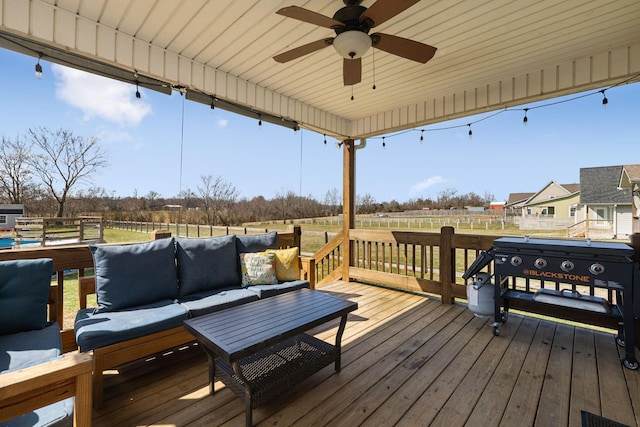 wooden terrace featuring fence, an outdoor living space, and a ceiling fan