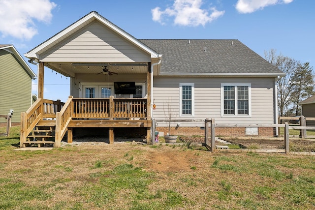rear view of house with a shingled roof, fence, a ceiling fan, a lawn, and a wooden deck