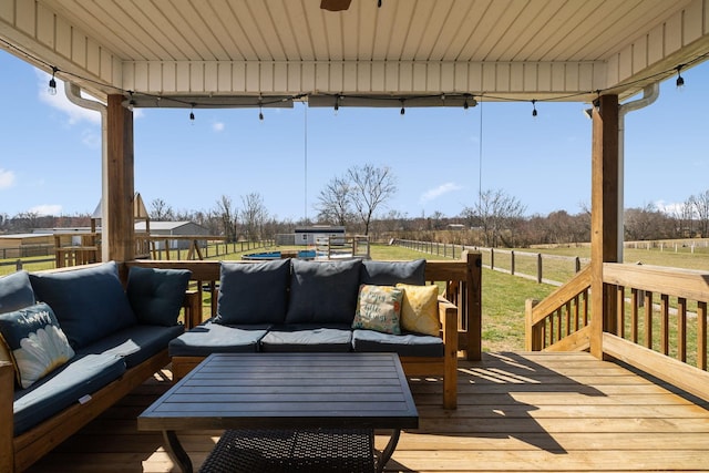 wooden deck featuring a rural view, fence, and an outdoor living space