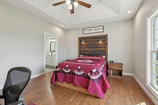 bedroom featuring a tray ceiling, baseboards, and wood finished floors