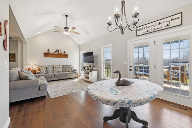 dining area with dark wood-style flooring, visible vents, vaulted ceiling, and ceiling fan with notable chandelier