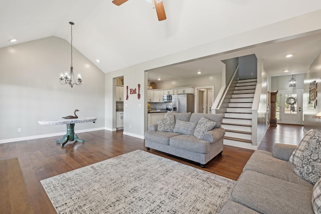 living room featuring lofted ceiling, ceiling fan with notable chandelier, baseboards, stairs, and dark wood-style floors