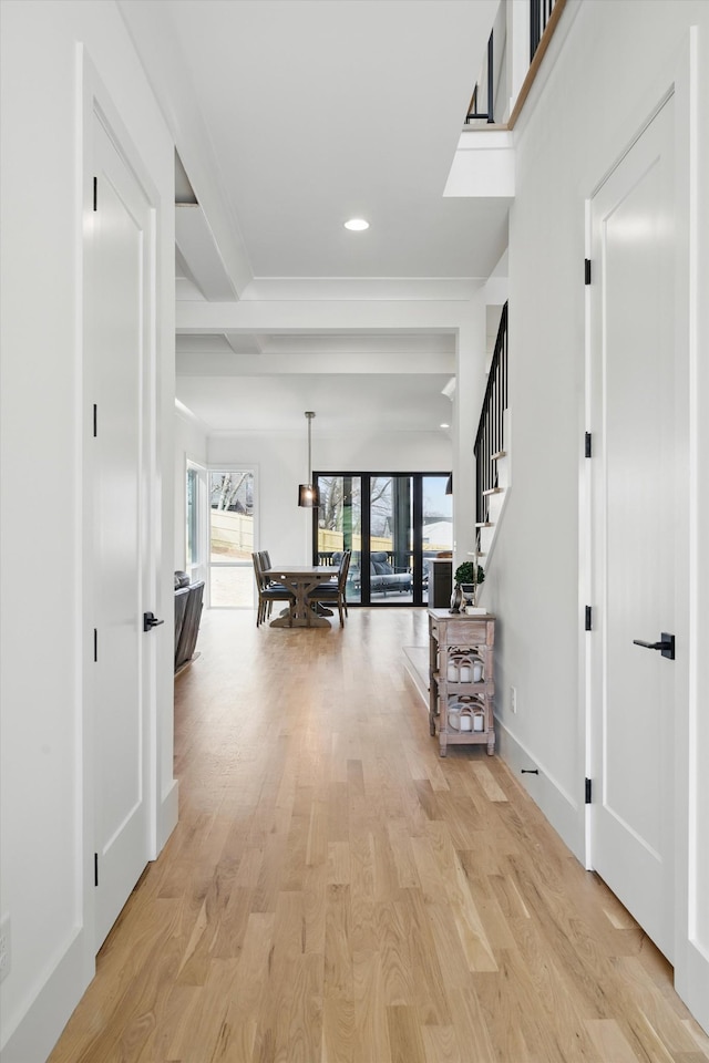 hallway with a skylight, recessed lighting, light wood-style floors, baseboards, and stairs