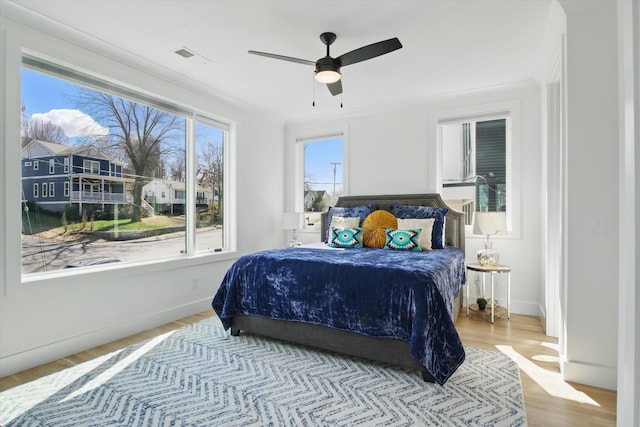 bedroom featuring visible vents, ceiling fan, baseboards, and wood finished floors