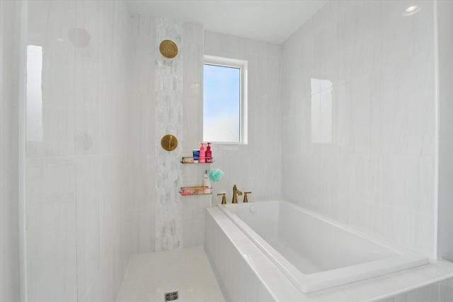 bathroom with a garden tub and tiled shower