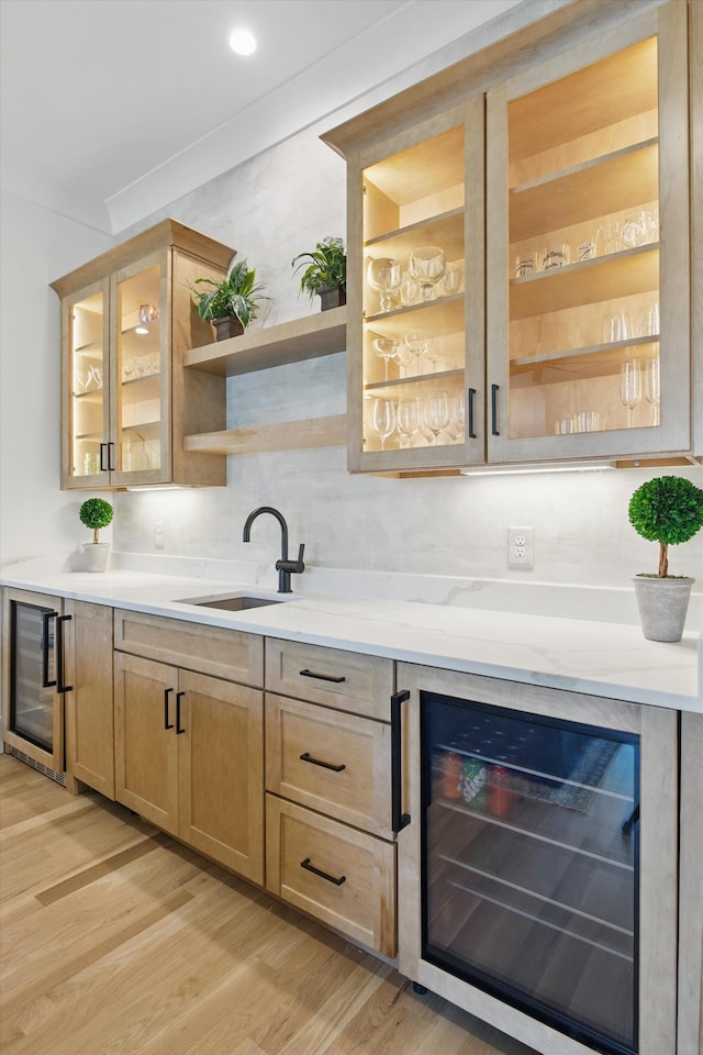 bar featuring wine cooler, light wood-type flooring, and a sink