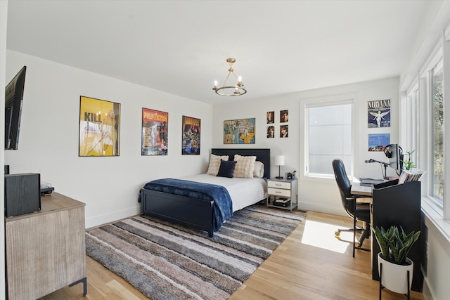 bedroom with an inviting chandelier, baseboards, and wood finished floors