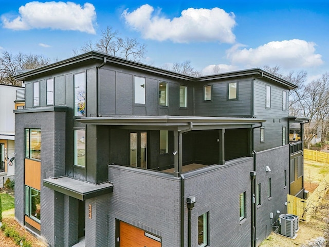 exterior space featuring a sunroom, cooling unit, and brick siding