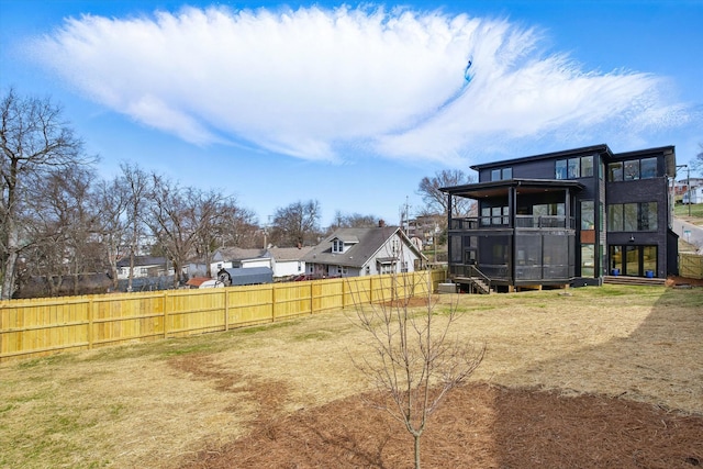 view of yard featuring a residential view, a sunroom, and fence