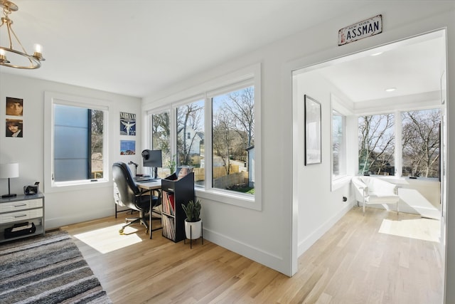 office space with a chandelier, light wood-type flooring, and baseboards