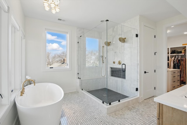 bathroom featuring a walk in closet, visible vents, a freestanding bath, a shower stall, and vanity